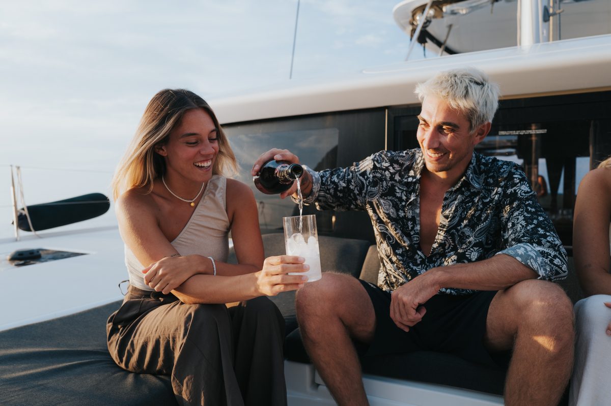 Two people on the catamaran deck pouring a drink