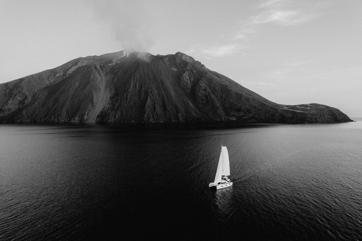 Catamaran sailing below Stromboli, black and white