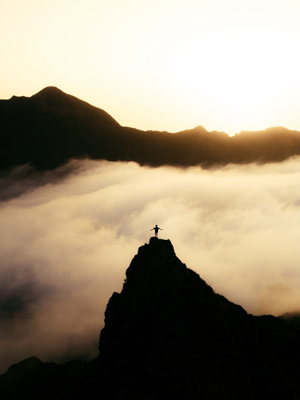 Person on a rocky summit above a sea of clouds