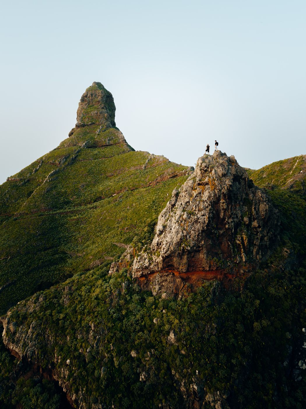 Two hikers on a green volcanic peak