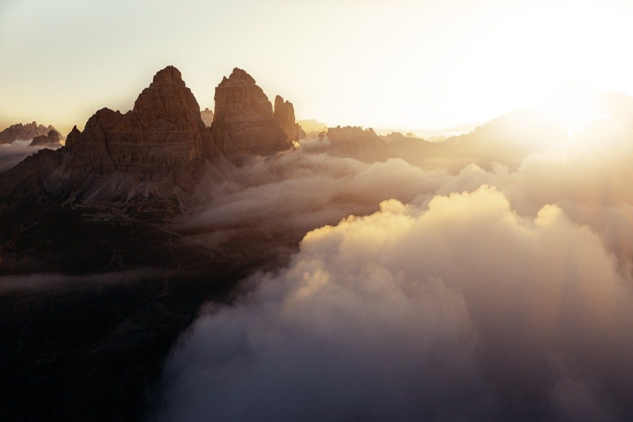Dolomite peaks rising above a sea of clouds at sunset